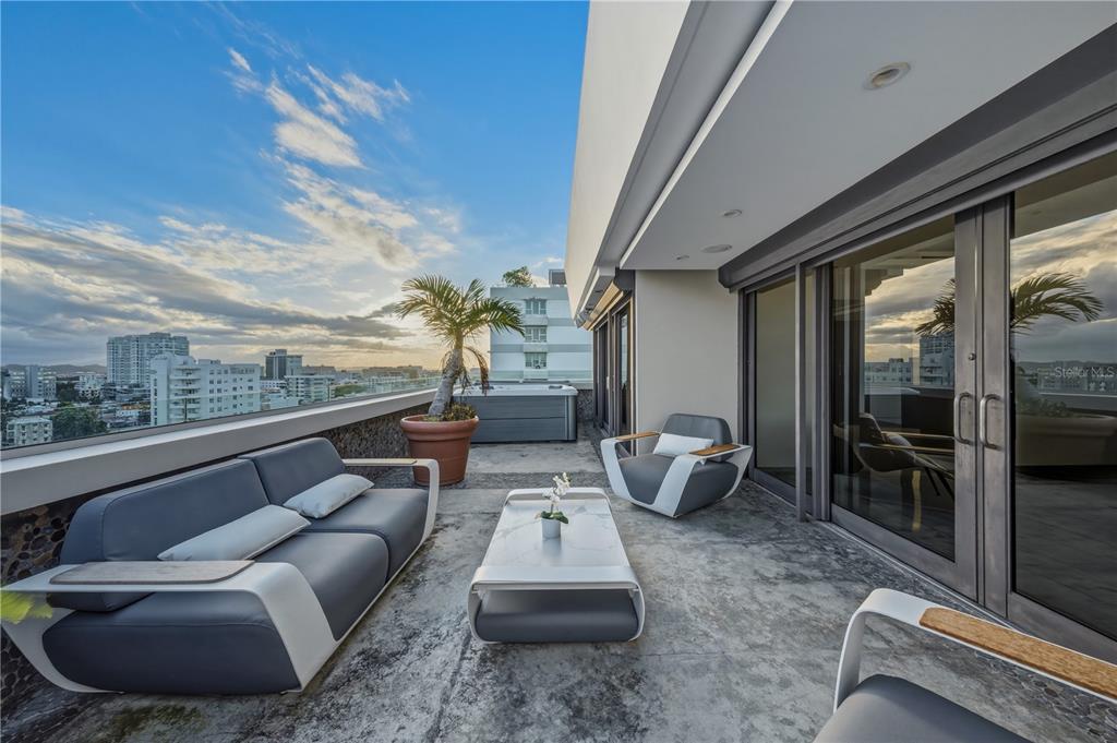 A modern balcony features outdoor seating, a hot tub, and a view of the city skyline — 1354 LUCHETTI STREET UNIT PH, SAN JUAN, PR