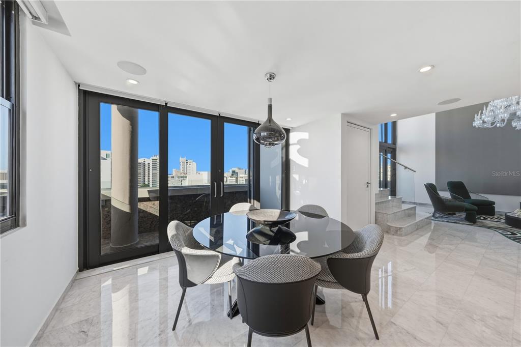 A dining area with a glass table, modern chairs, marble floors, and floor-to-ceiling windows — 1354 LUCHETTI STREET UNIT PH, SAN JUAN, PR
