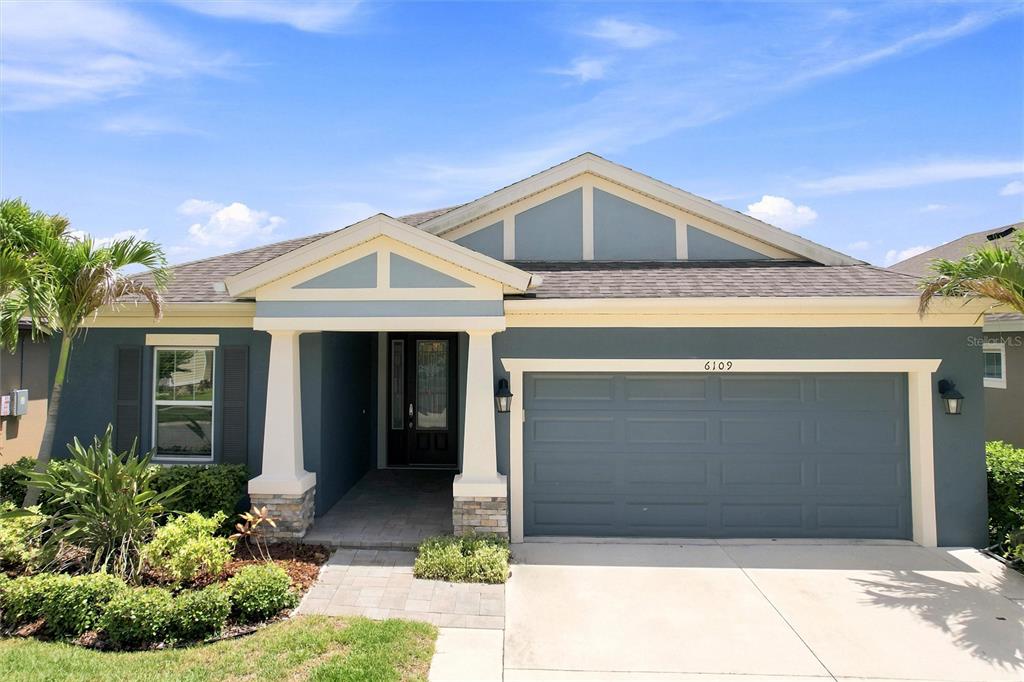 A single-story house with blue siding, a two-car garage, and a covered front entryway — 6109 COLMAR PLACE, APOLLO BEACH, FL