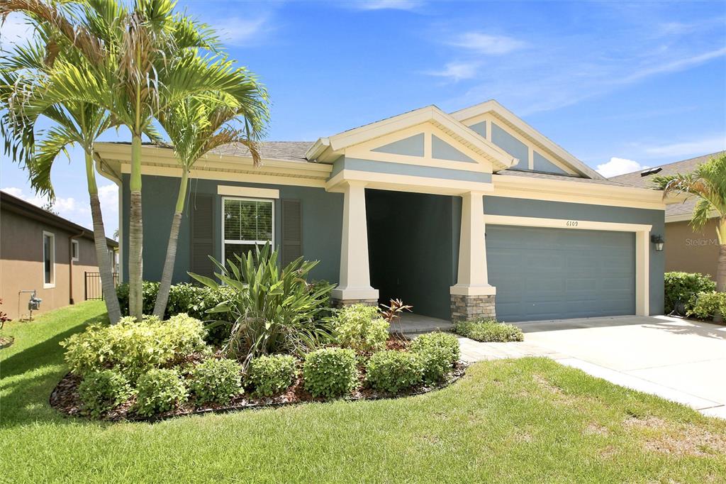 A single-story house with a blue exterior, a two-car garage, and a palm tree — 6109 COLMAR PLACE, APOLLO BEACH, FL