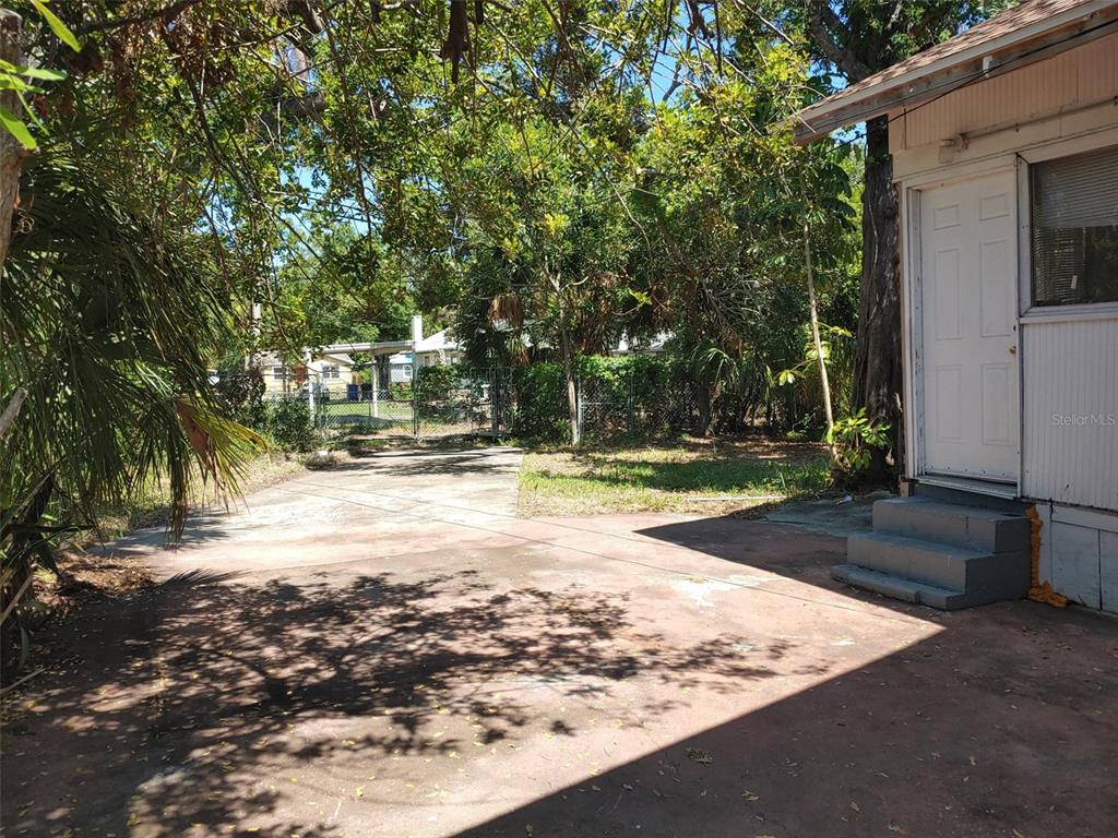 A concrete driveway leads to the side entrance of a house with gray steps — 1924 30TH STREET S, ST PETERSBURG, FL