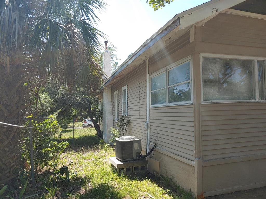 The exterior side of a house features beige siding, a chimney, and an air conditioning unit — 1924 30TH STREET S, ST PETERSBURG, FL