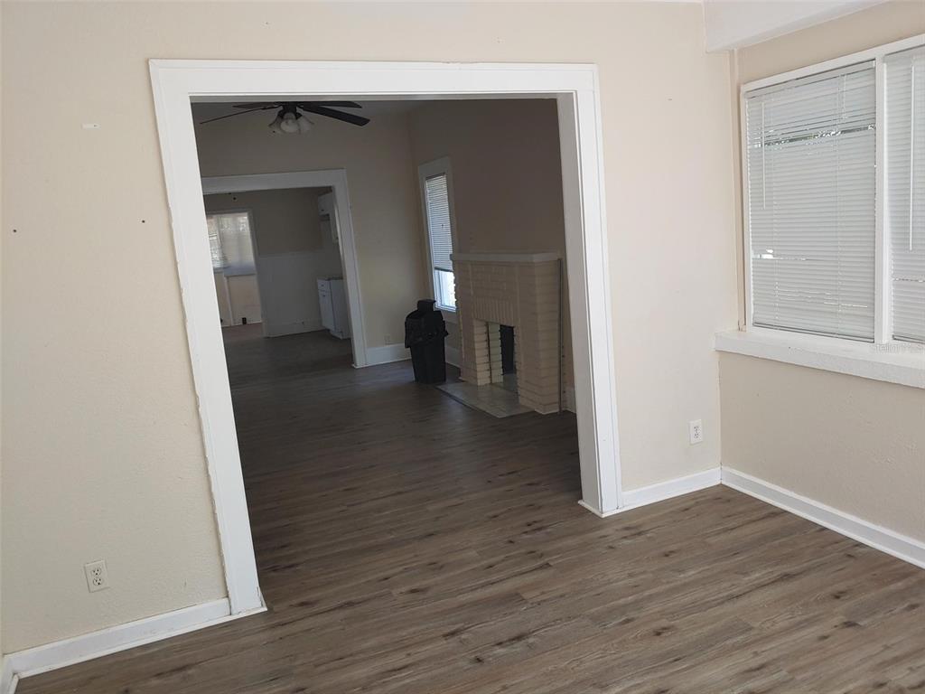 An interior view shows a living room with wood-look flooring leading to a fireplace area — 1924 30TH STREET S, ST PETERSBURG, FL