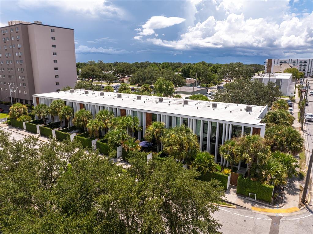 An aerial view shows a modern multi-unit residential building surrounded by palm trees and landscaping — 154 2ND STREET SW Unit 7, WINTER HAVEN, FL