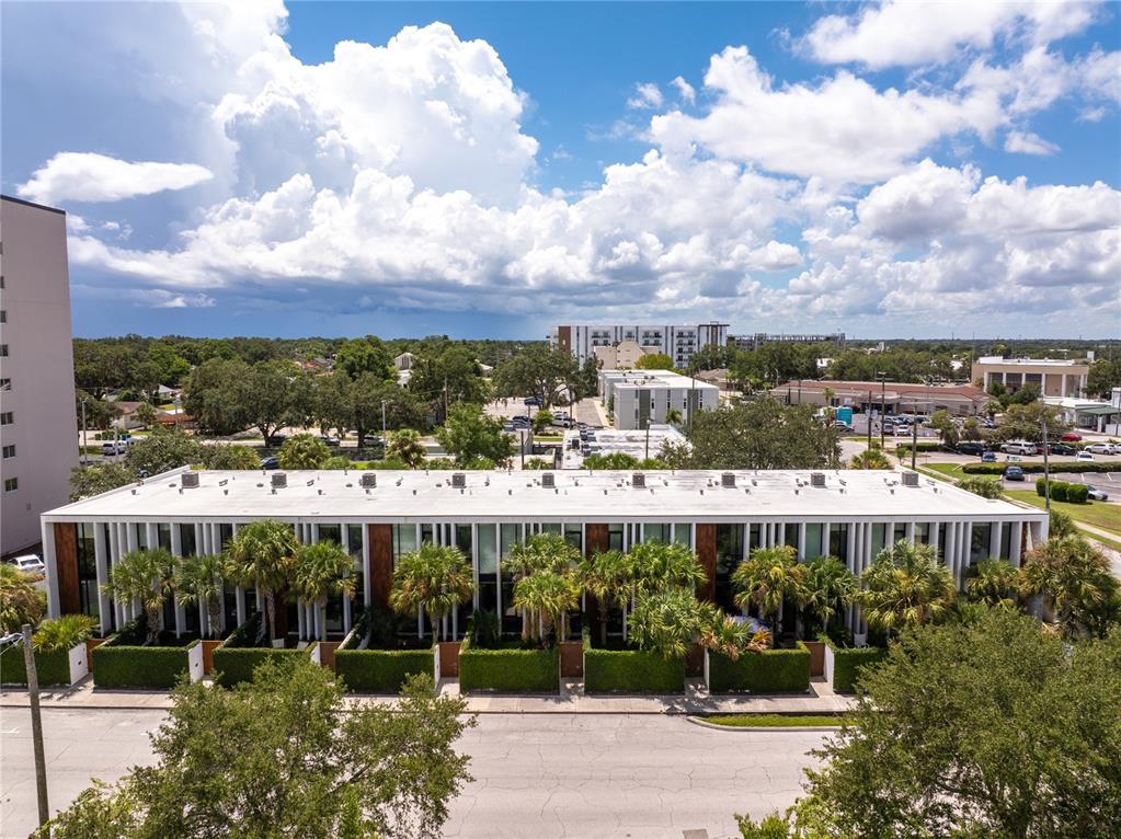 An aerial view shows a modern multi-unit residential building with white vertical accents and landscaping — 154 2ND STREET SW Unit 7, WINTER HAVEN, FL