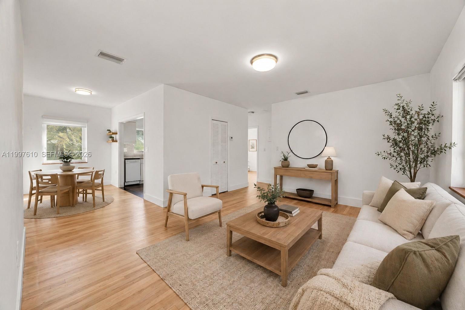 A bright living and dining area features white walls, hardwood floors, and neutral furniture — 5510 SW 76th St # C, Miami FL 33143, MIAMI, FL