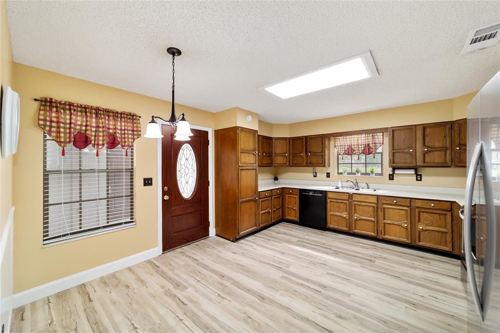 A kitchen with wood cabinets, white countertops, light wood-look flooring, and a dining area — 4508 SE 2ND PLACE, OCALA, FL
