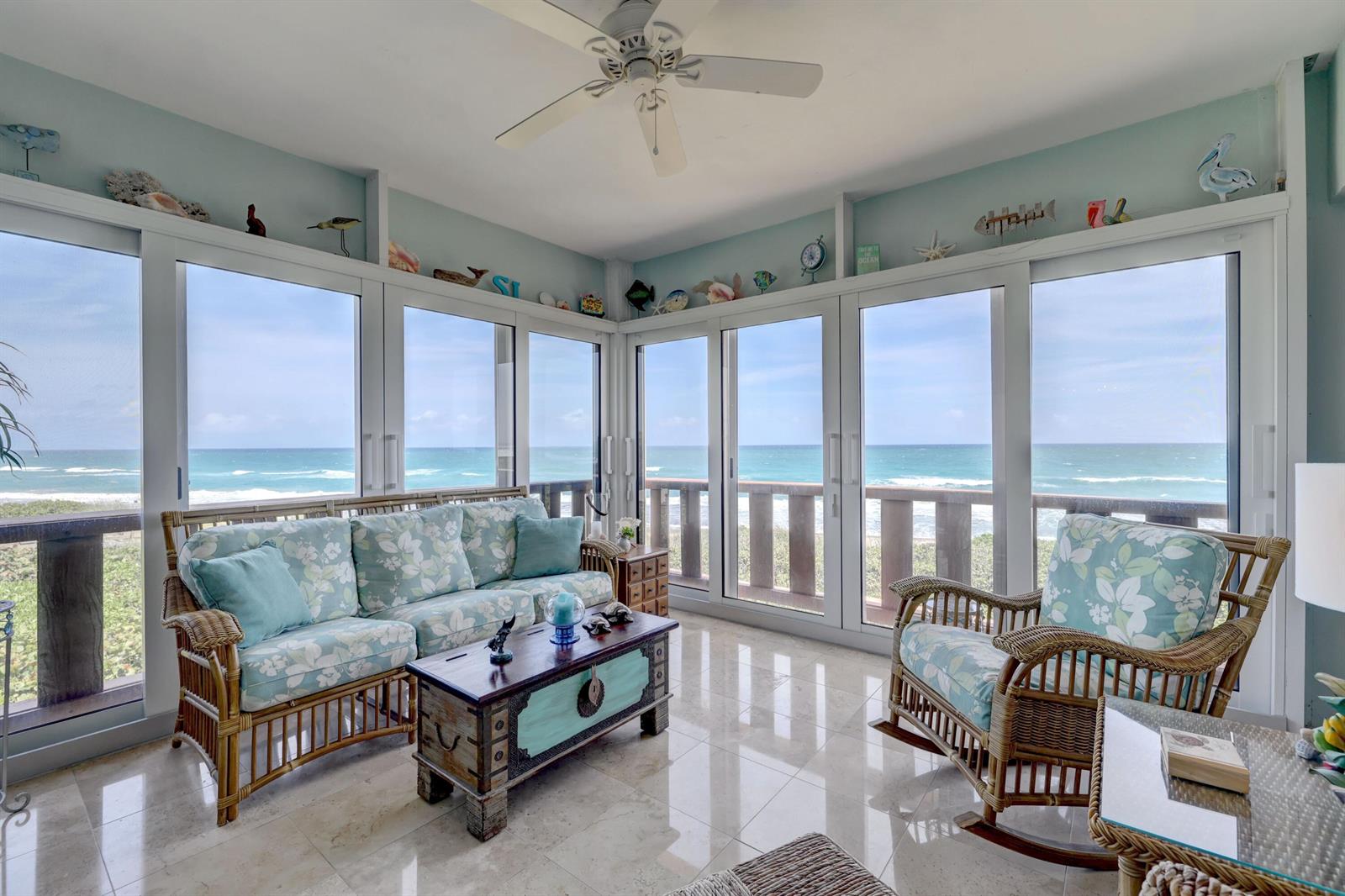 A sunroom with wicker furniture, floral cushions, and large windows overlooking the ocean — 1555 NE Ocean Boulevard # 205, Stuart FL 34996, STUART, FL