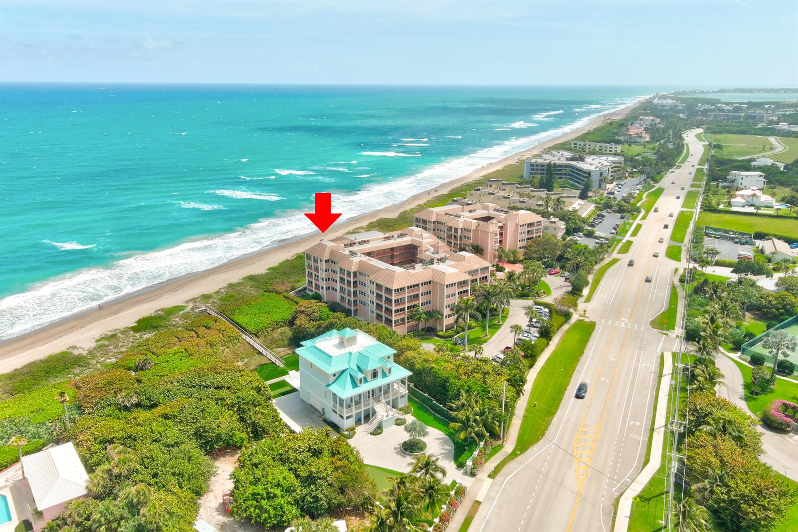 An aerial view shows a beachfront condominium complex and a nearby house along the coast — 1555 NE Ocean Boulevard # 205, Stuart FL 34996, STUART, FL
