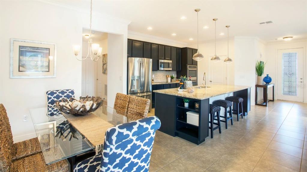 A kitchen with dark cabinets and a granite island sits adjacent to a dining area — 25147 CALUSA DRIVE, PUNTA GORDA, FL