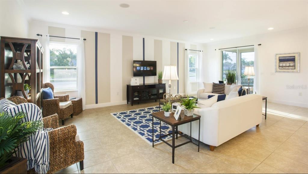 A living room features a striped accent wall, a television, and white furniture on tile — 25147 CALUSA DRIVE, PUNTA GORDA, FL