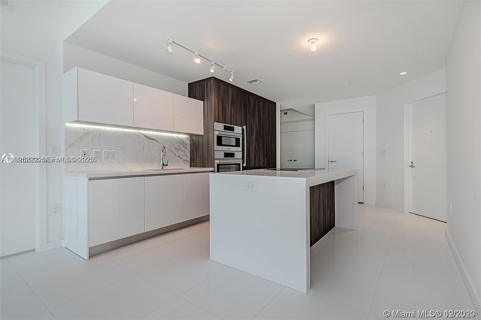 A modern kitchen features white cabinets, a marble backsplash, and a central island — 851 NE 1st Ave # 1608, Miami FL 33132, MIAMI, FL