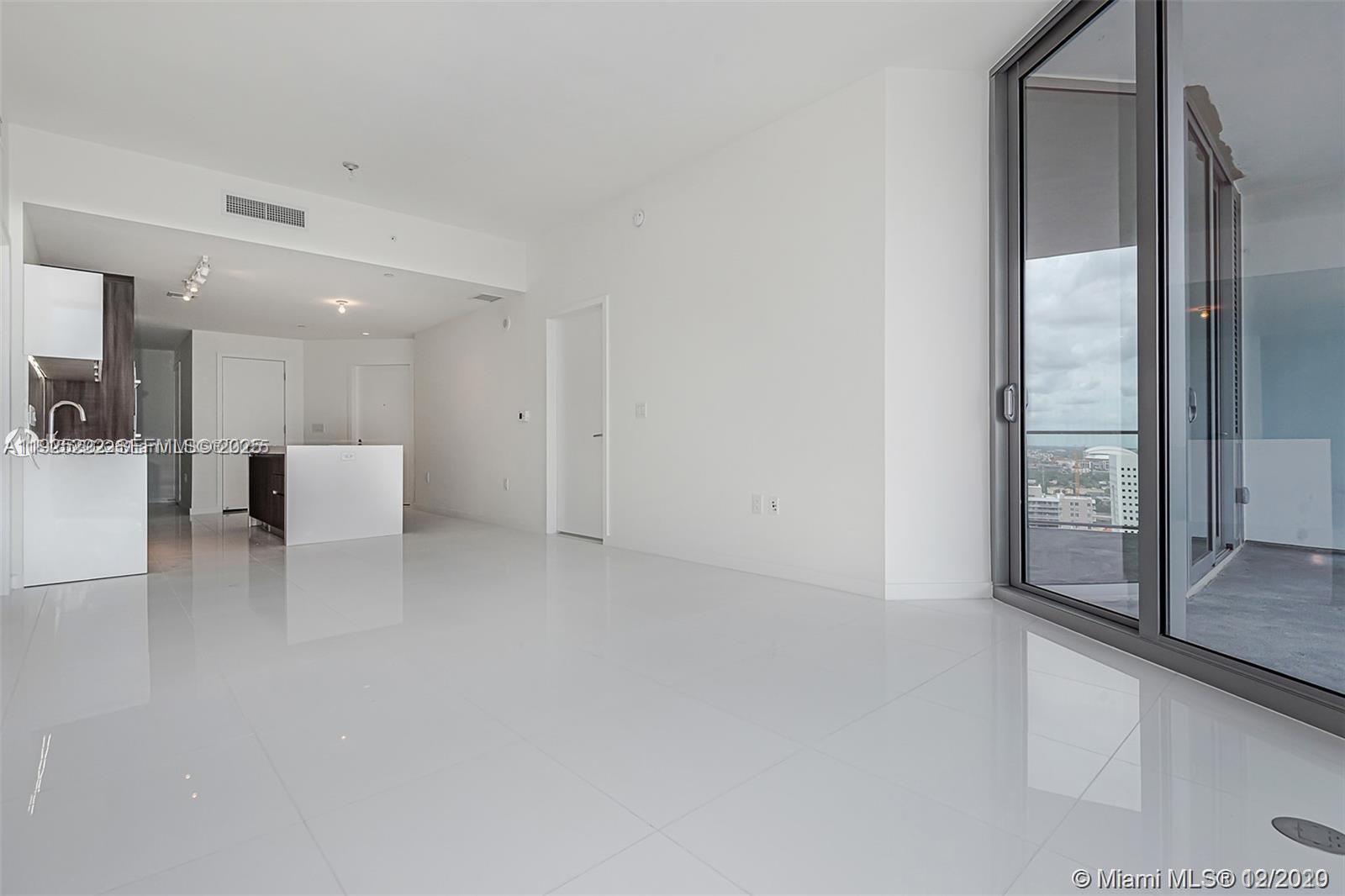 A modern, minimalist living area with white tile floors, a kitchen, and a balcony view — 851 NE 1st Ave # 1608, Miami FL 33132, MIAMI, FL