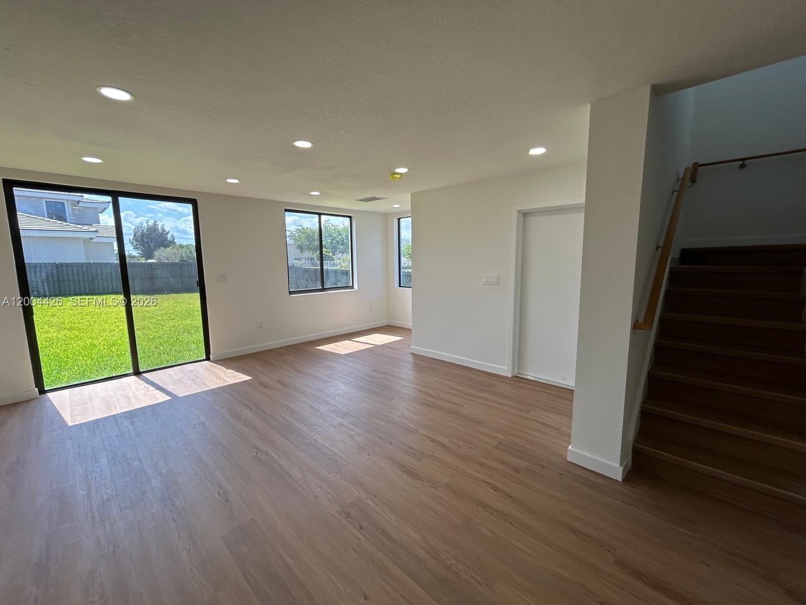An open-concept kitchen with gray cabinets and stainless steel appliances overlooks a living area — 12556 SW 194th St # 0, Miami FL 33177, MIAMI, FL