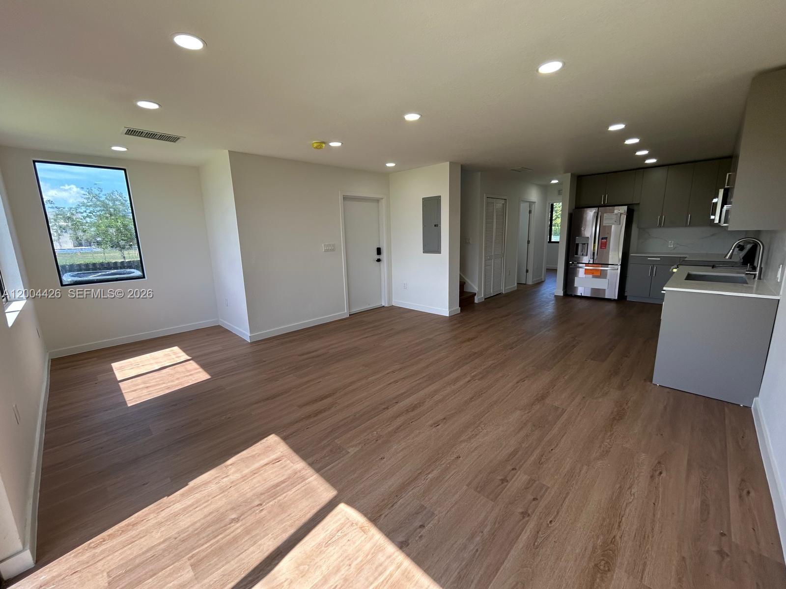 An open-concept living area features light wood-look flooring and a modern kitchen with gray cabinetry — 12556 SW 194th St # 0, Miami FL 33177, MIAMI, FL