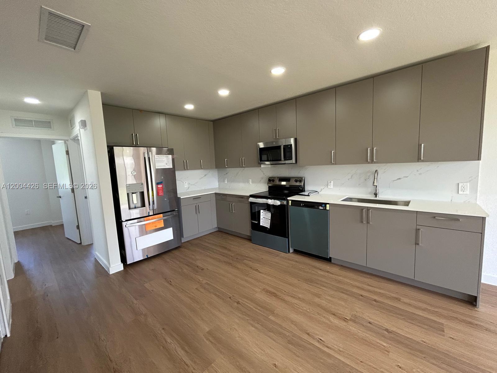 A modern kitchen features gray flat-panel cabinets, stainless steel appliances, and white marble-look countertops — 12556 SW 194th St # 0, Miami FL 33177, MIAMI, FL