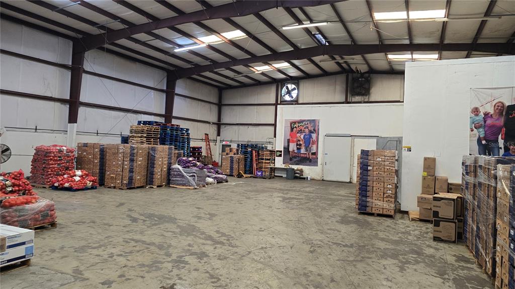 A large warehouse interior features concrete floors, exposed metal beams, and stacks of palletized goods — 100 ORANGE CO CIRCLE, WINTER HAVEN, FL