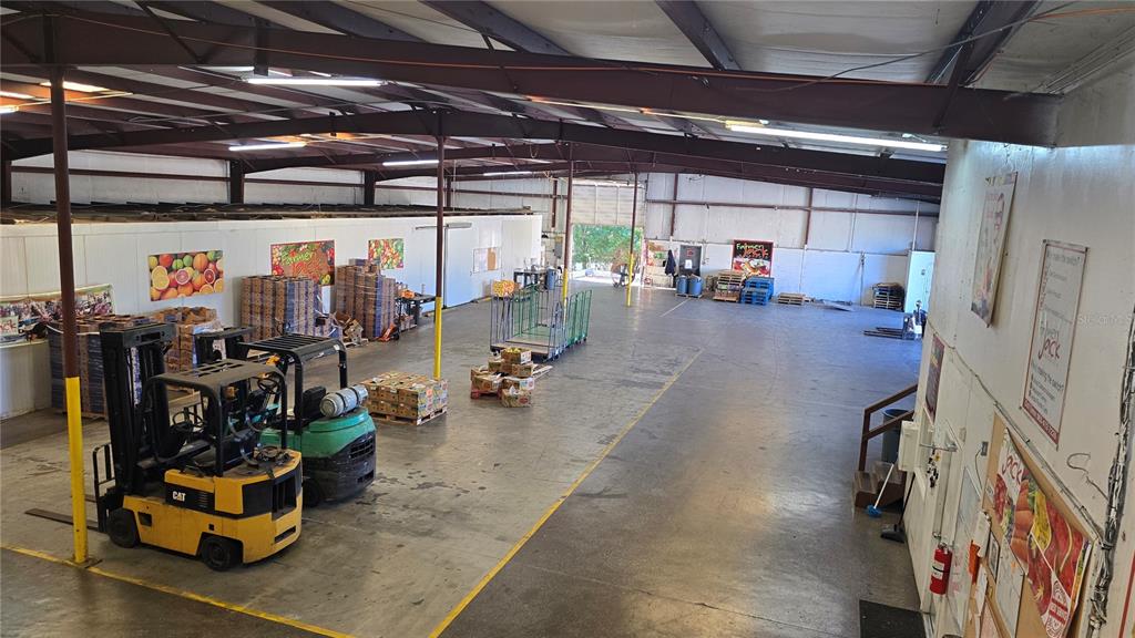 An interior view of a large warehouse featuring concrete floors, forklifts, and stacked produce crates — 100 ORANGE CO CIRCLE, WINTER HAVEN, FL