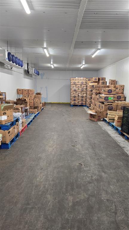 A large, industrial walk-in freezer features concrete floors, white panel walls, and stacked cardboard boxes — 100 ORANGE CO CIRCLE, WINTER HAVEN, FL