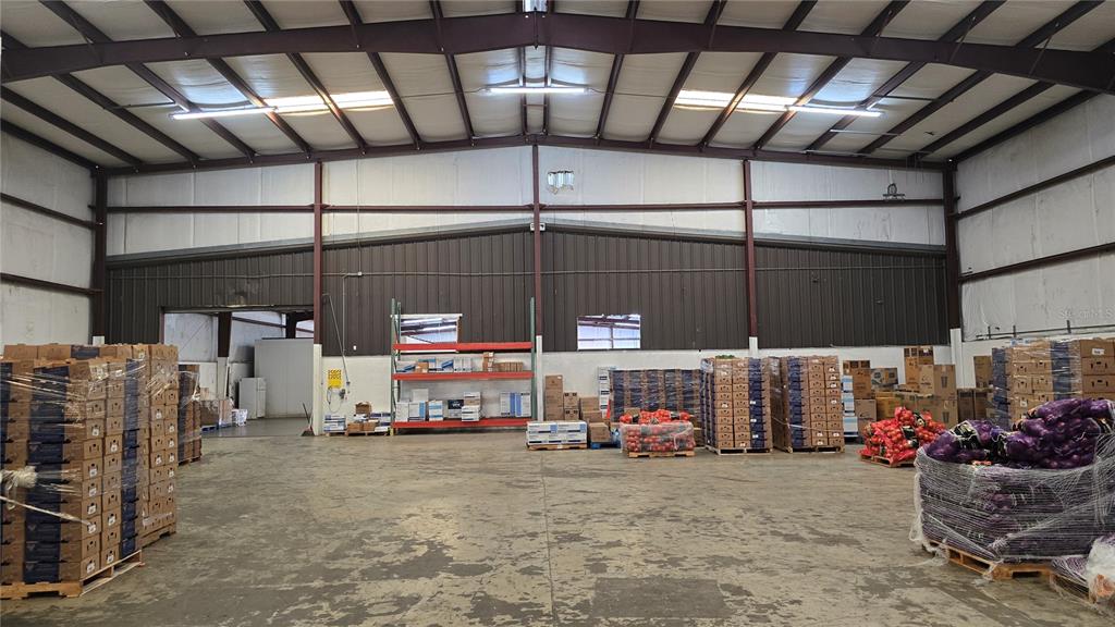 A large warehouse interior features concrete floors, metal walls, and stacks of palletized goods — 100 ORANGE CO CIRCLE, WINTER HAVEN, FL
