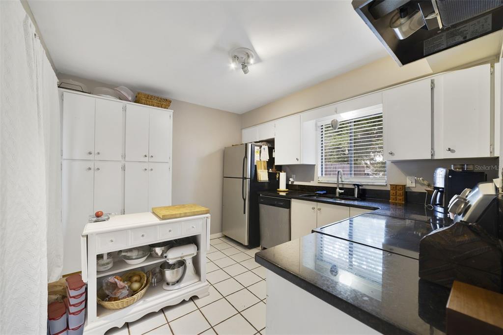 A kitchen features white cabinets, black countertops, stainless steel appliances, and a white kitchen island — 5909 TURNBULL DRIVE, ORLANDO, FL