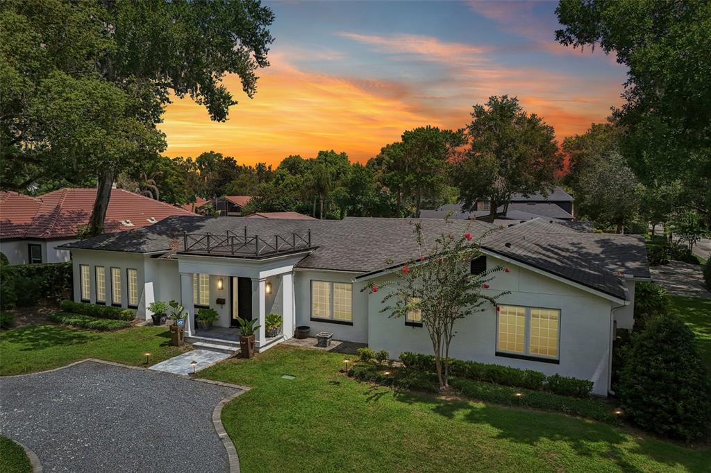A white single-story house with a dark shingled roof and a gravel driveway at sunset — 1271 PALMER AVENUE, WINTER PARK, FL
