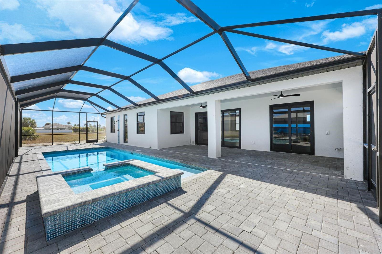 A screened-in patio features a swimming pool, a raised spa, and gray paver flooring — 1925 NW 34th Place, Cape Coral FL 33993, CAPE CORAL, FL