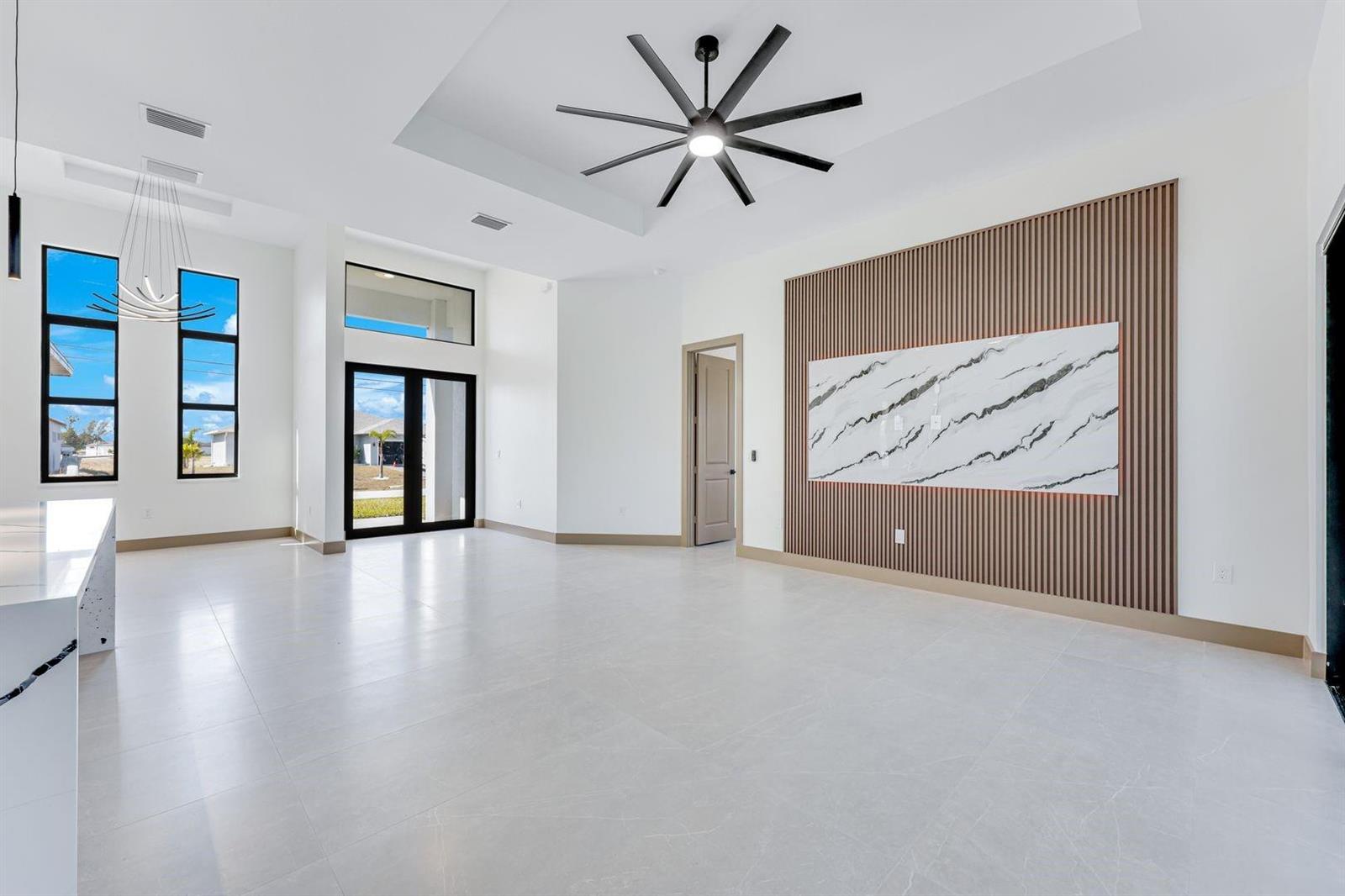 A bright, modern living room features a marble accent wall, wood slats, and tile flooring — 1925 NW 34th Place, Cape Coral FL 33993, CAPE CORAL, FL