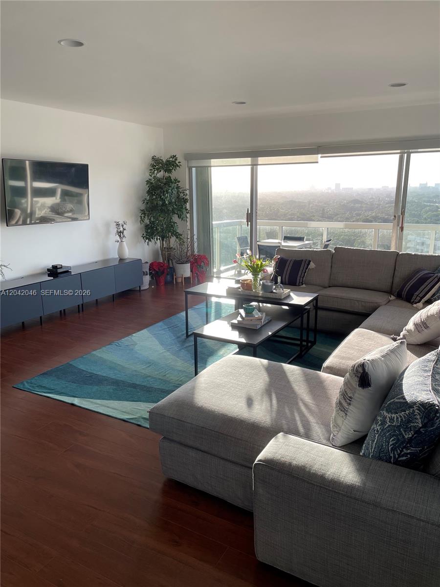 A living room features a grey sectional sofa, a blue area rug, and a balcony view — 2451 Brickell Ave # 20M, Miami FL 33129, MIAMI, FL