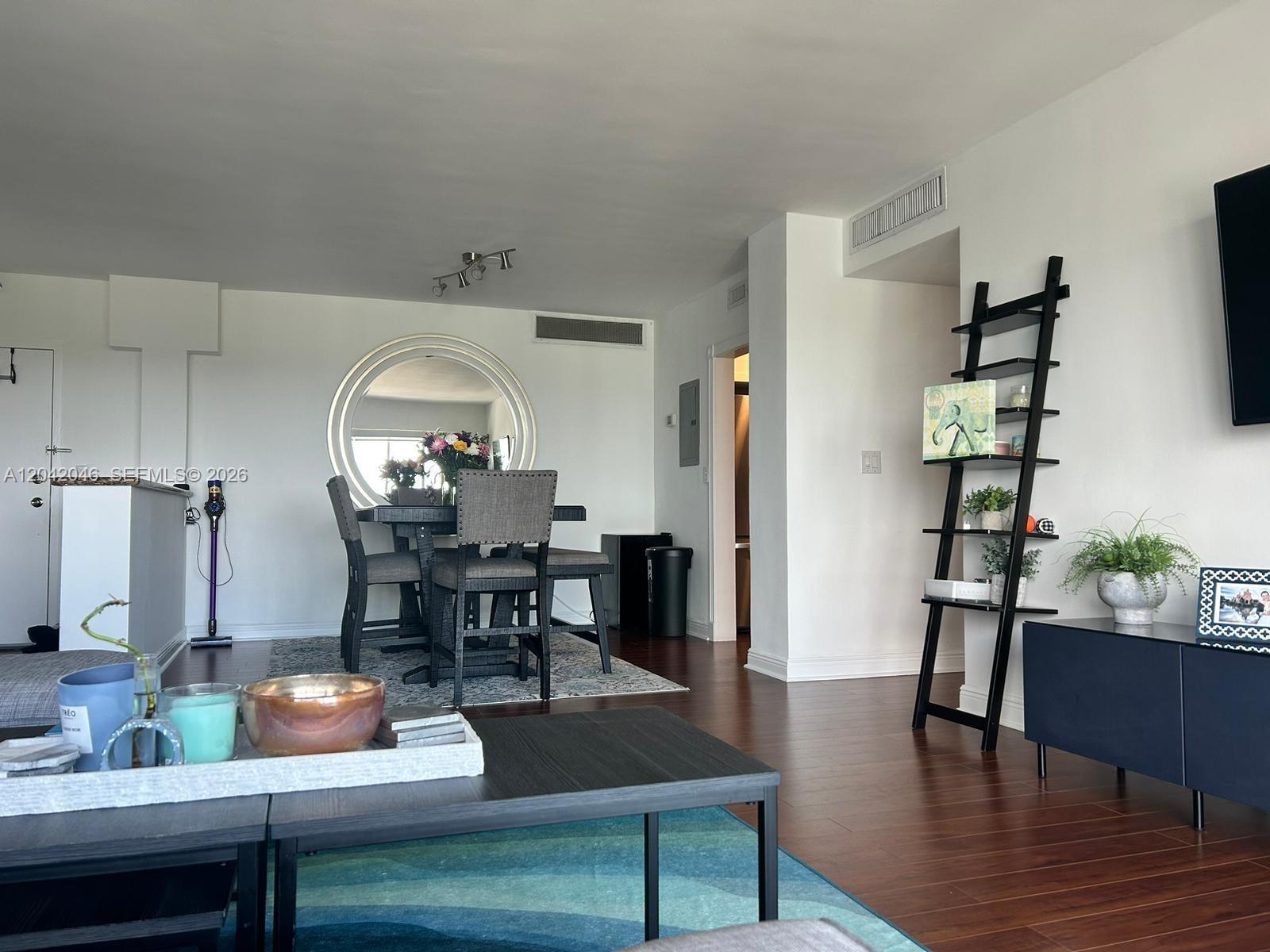 A dining area with a round mirror and a living room with a ladder shelf — 2451 Brickell Ave # 20M, Miami FL 33129, MIAMI, FL