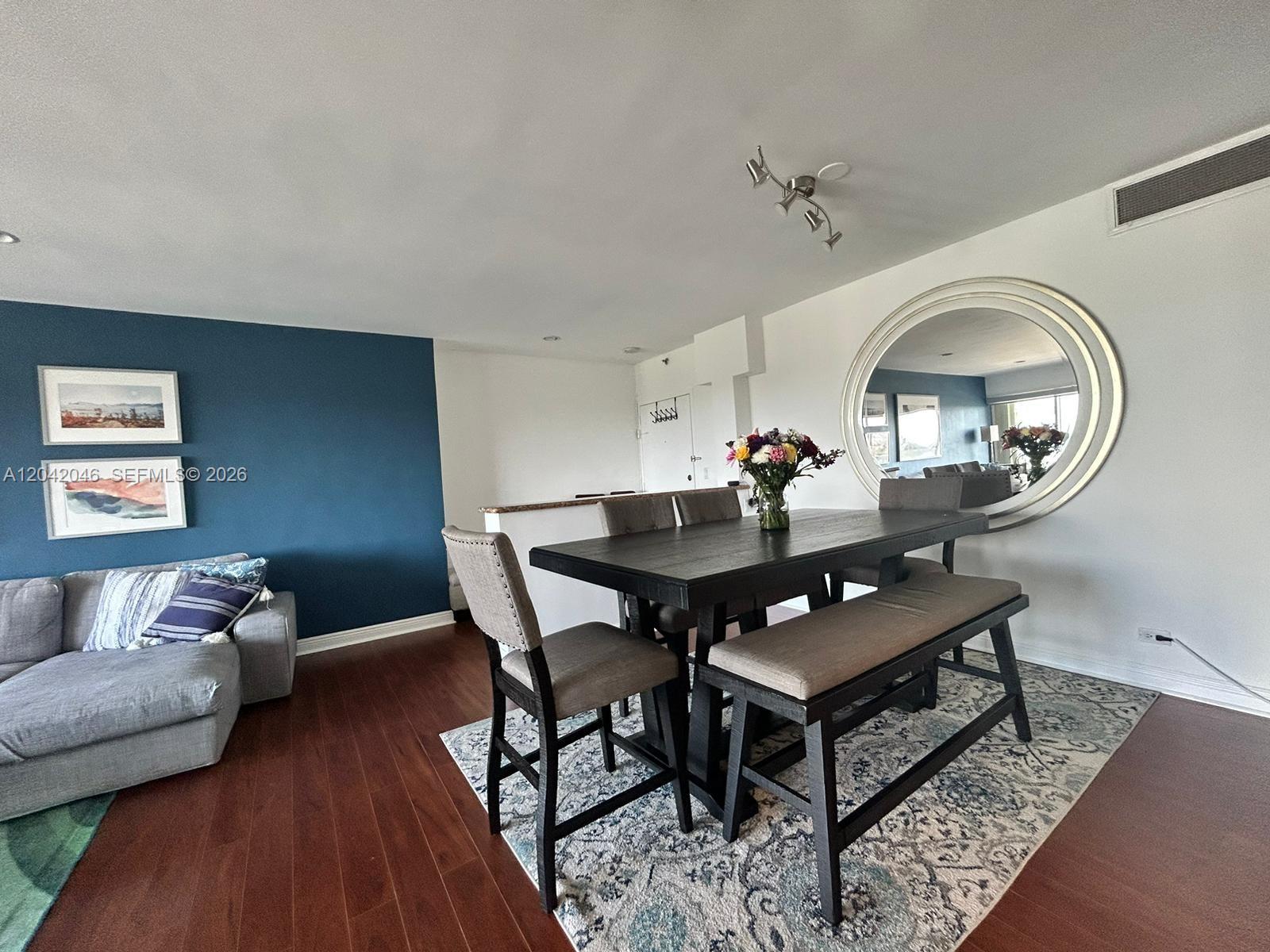 A dining area features a dark wood table, upholstered chairs, a bench, and a large mirror — 2451 Brickell Ave # 20M, Miami FL 33129, MIAMI, FL