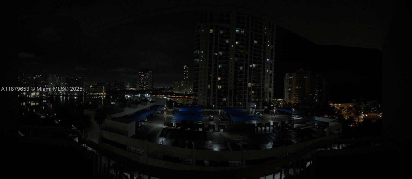 A night view from a balcony overlooking a parking lot and surrounding high-rise buildings — 1965 S Ocean Dr # 7D, Hallandale Beach FL 33009, HALLANDALE BEACH, FL