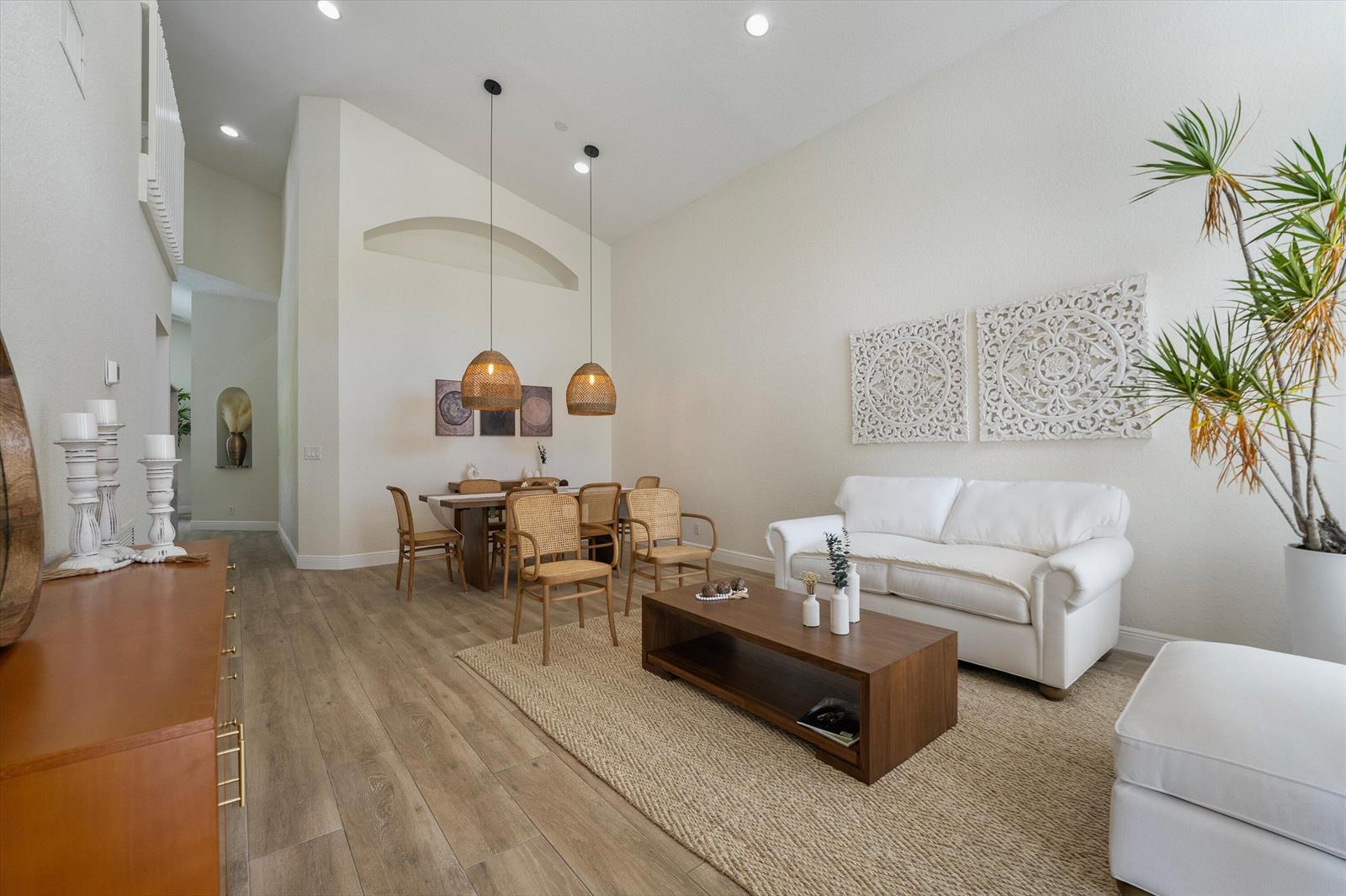 A living and dining area features white walls, wood-look flooring, a white sofa, and rattan chairs — 4033 Bluff Harbor Way, Wellington FL 33449, WELLINGTON, FL