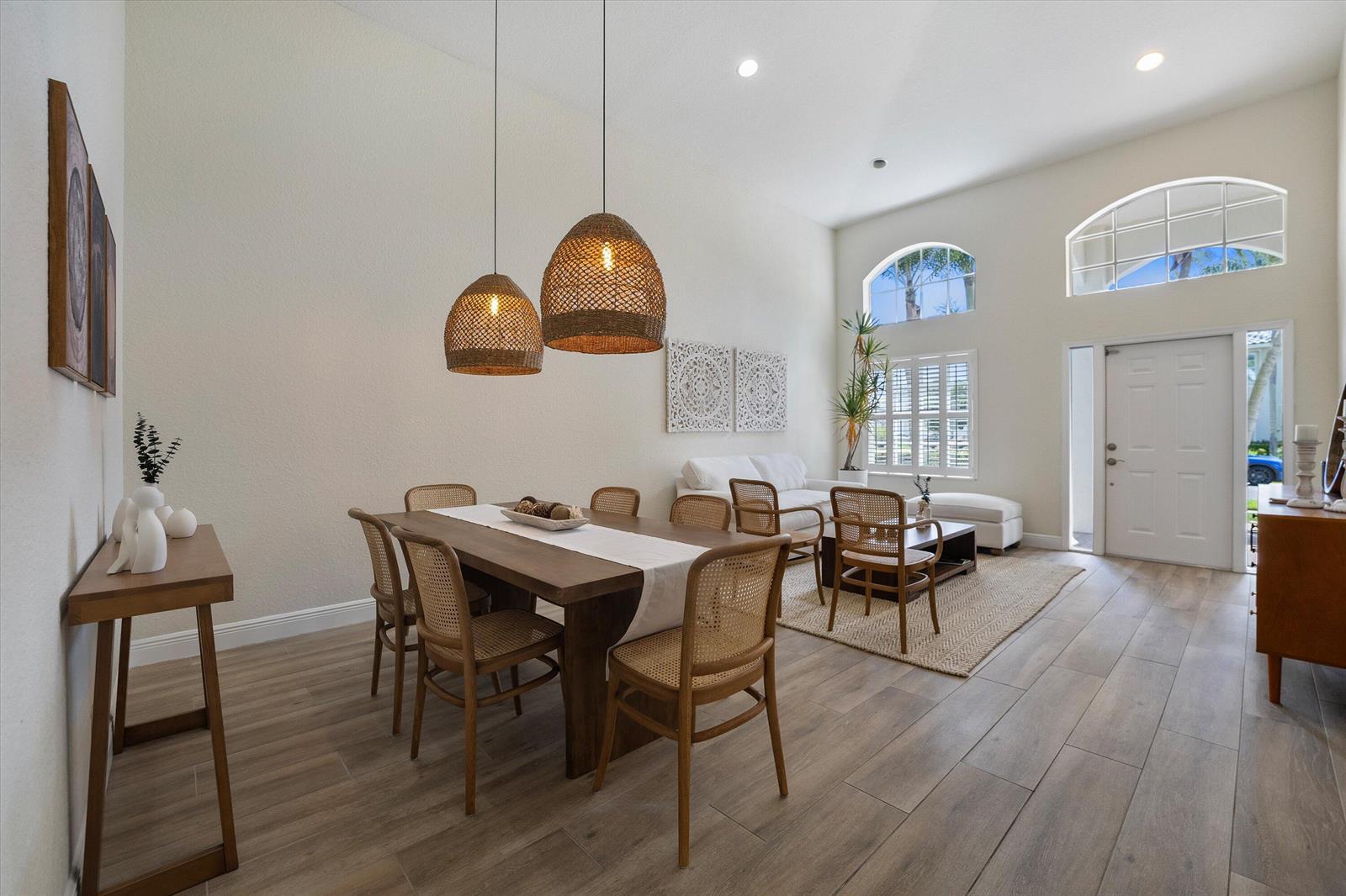 A dining area and living room feature wood-look flooring, cane chairs, and high vaulted ceilings — 4033 Bluff Harbor Way, Wellington FL 33449, WELLINGTON, FL