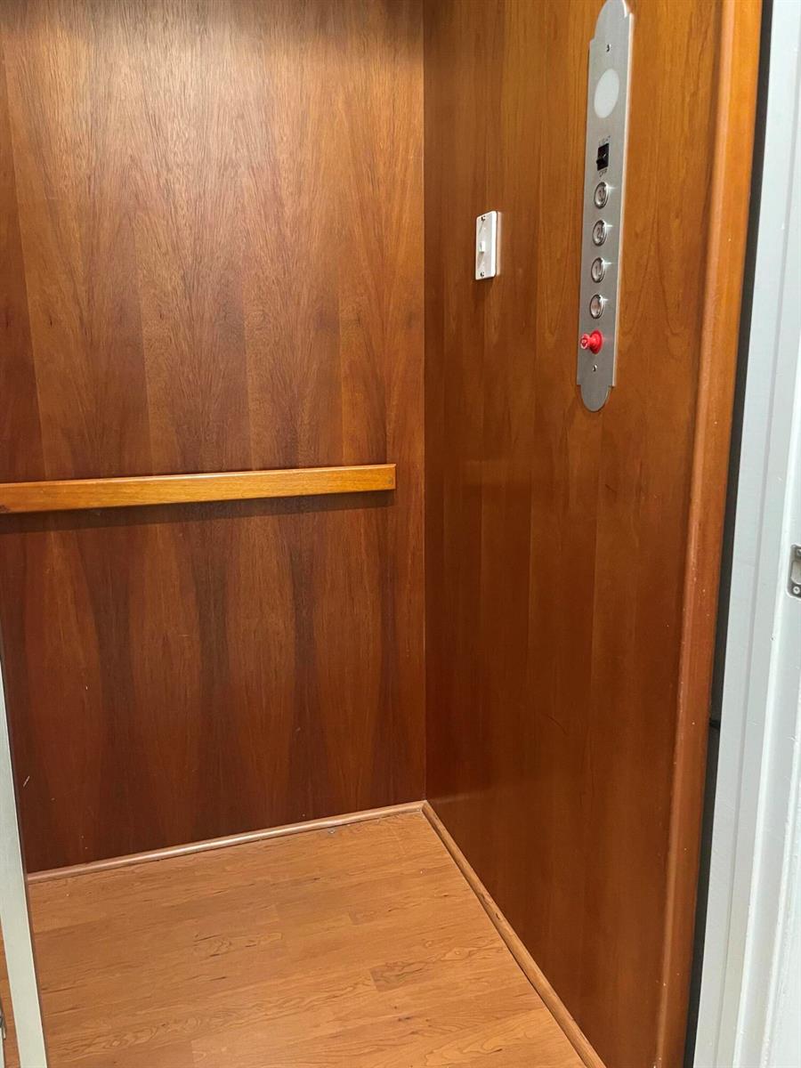 An elevator interior featuring wood-paneled walls, a wood floor, and a vertical control panel — 552 NW 39th Circle N, Boca Raton FL 33431, BOCA RATON, FL
