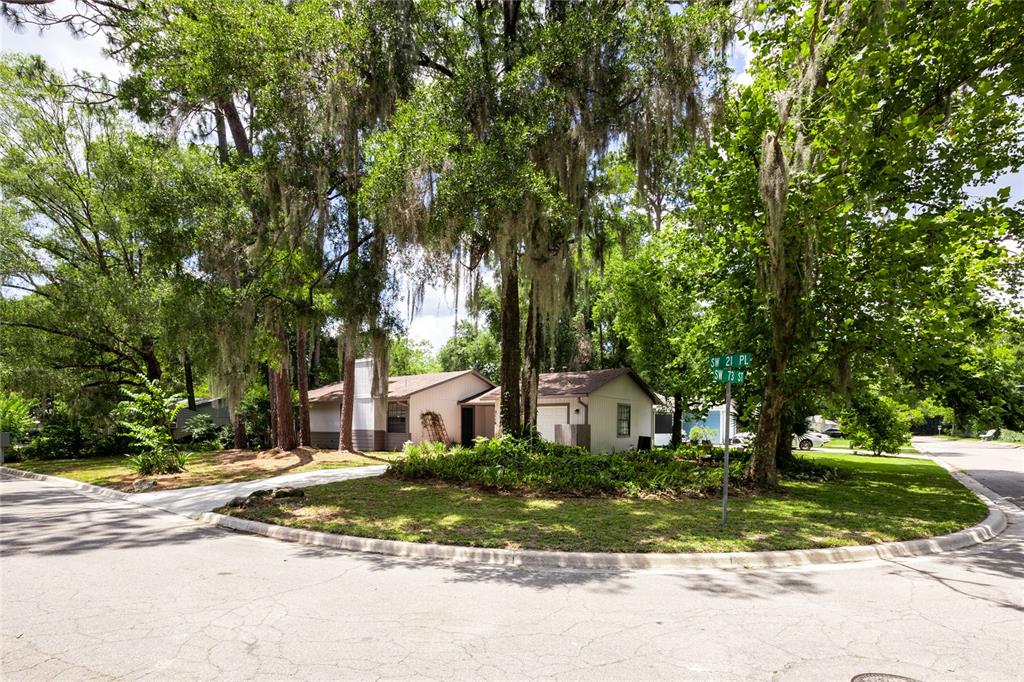 A blue front door with a brass knocker sits under a covered porch with siding — 2116 SW 73RD STREET, GAINESVILLE, FL