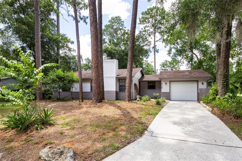 A living room features a white fireplace, wood flooring, a ceiling fan, and two windows — 2116 SW 73RD STREET, GAINESVILLE, FL