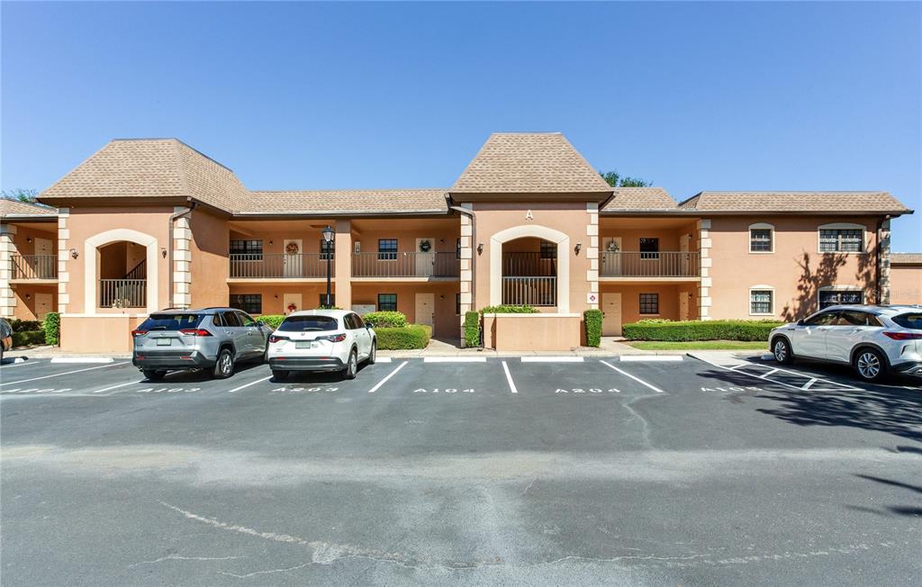 A two-story apartment building with a tan stucco exterior and a parking lot in front — 12900 VONN ROAD UNIT A204, LARGO, FL