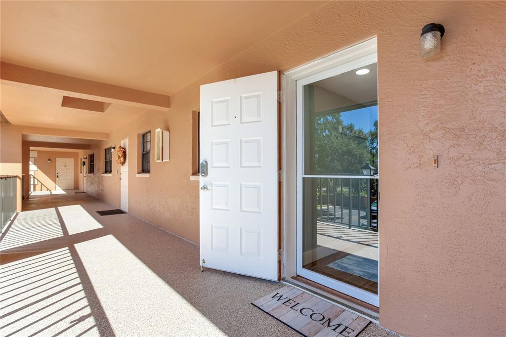 An open white door leads into a home from a covered outdoor walkway — 12900 VONN ROAD UNIT A204, LARGO, FL