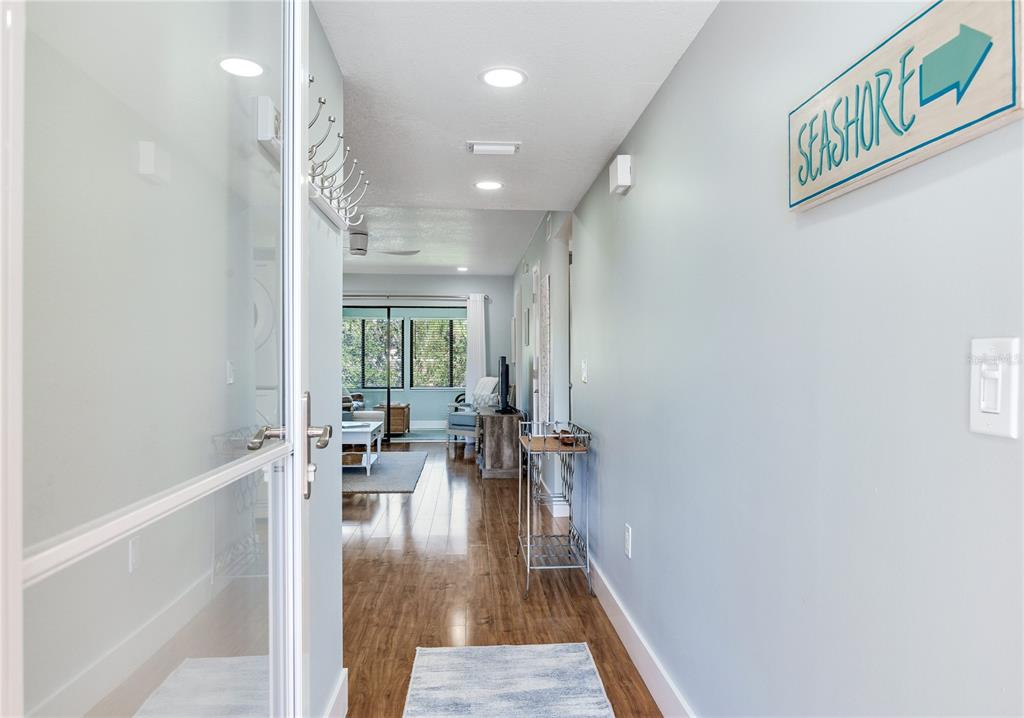 A view from a doorway looking down a hallway into a living room with wood floors — 12900 VONN ROAD UNIT A204, LARGO, FL