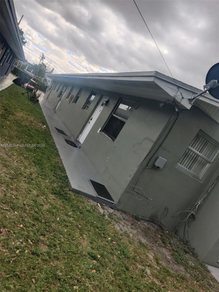 A side view of a single-story gray building with a concrete walkway and grass — 844 SW 10th St, Hallandale Beach FL 33009, HALLANDALE BEACH, FL