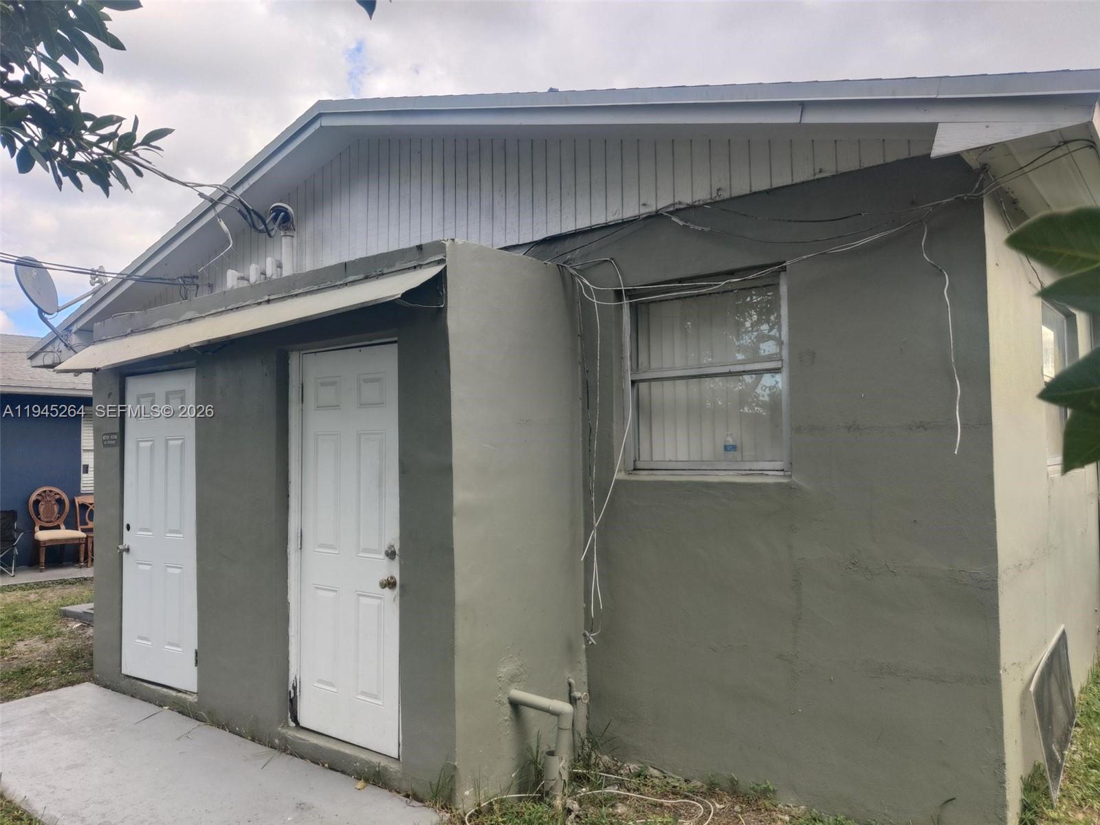The exterior of a gray stucco building features two white doors and a window — 844 SW 10th St, Hallandale Beach FL 33009, HALLANDALE BEACH, FL