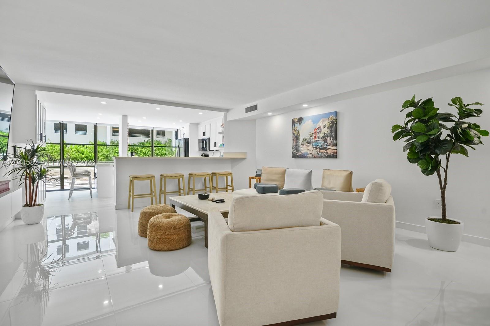 A bright, open-concept living room features white tile floors, a kitchen breakfast bar, and furniture — 6423 Collins Ave # 203, Miami Beach FL 33141, MIAMI BEACH, FL