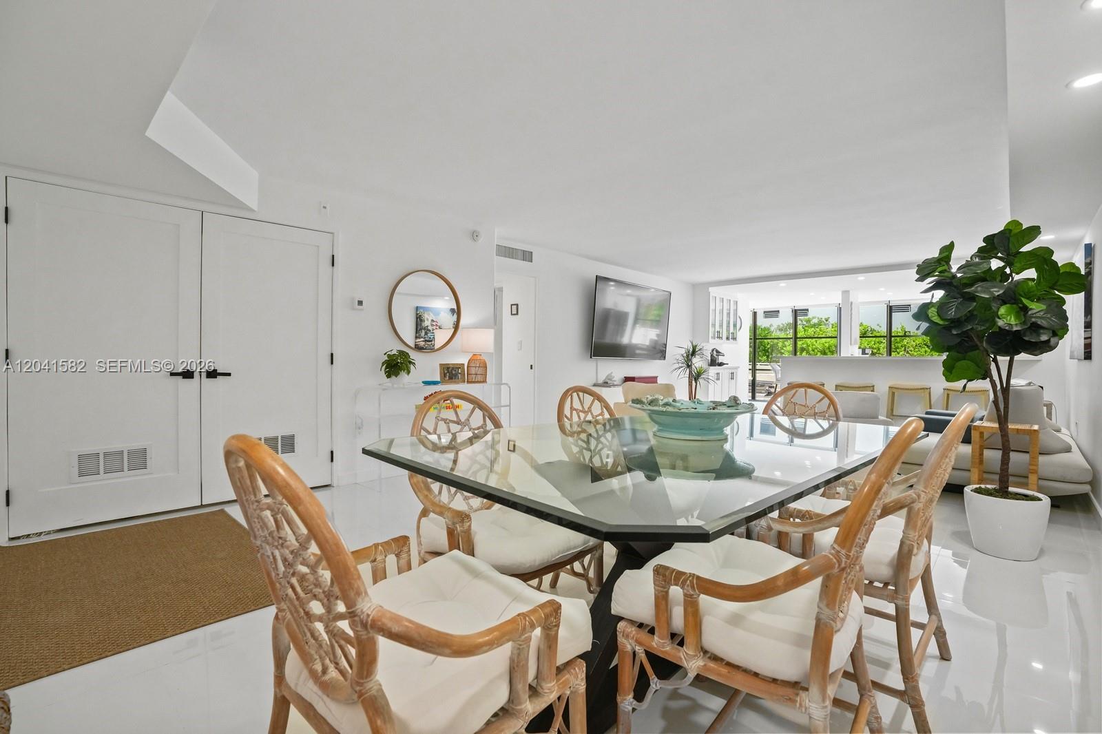 A dining area features a glass-topped table with rattan chairs and white tile flooring — 6423 Collins Ave # 203, Miami Beach FL 33141, MIAMI BEACH, FL