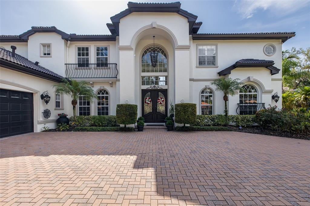 A two-story stucco house with a paved driveway, arched entryway, and dark-framed windows — 10628 PONTOFINO CIRCLE, TRINITY, FL