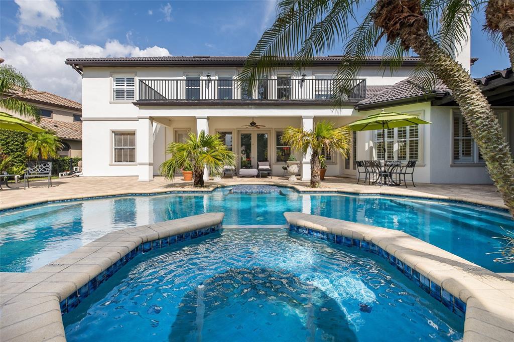 An aerial view of a backyard swimming pool with a spa and surrounding paver patio — 10628 PONTOFINO CIRCLE, TRINITY, FL