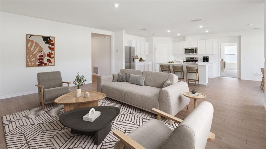 A bright, open-concept living room and kitchen feature light wood flooring and neutral furniture — 24282 NW 13TH BOULEVARD, NEWBERRY, FL