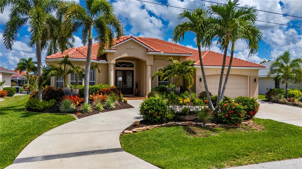 An aerial view shows a residential neighborhood with a canal and a house with a red-tiled roof — 1020 VIA FORMIA, PUNTA GORDA, FL