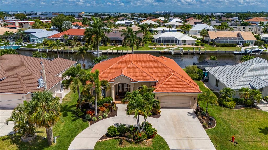 An aerial view of a waterfront house with a pool, screened lanai, and boat dock — 1020 VIA FORMIA, PUNTA GORDA, FL