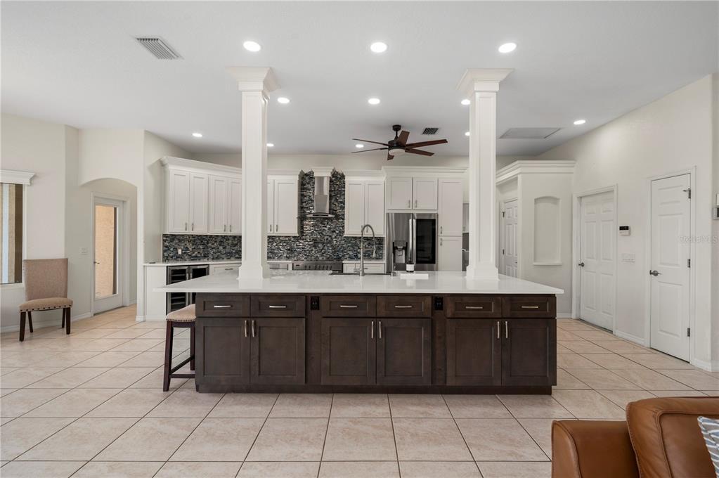 A kitchen with a large dark wood island, white cabinets, and two structural support columns — 1020 VIA FORMIA, PUNTA GORDA, FL